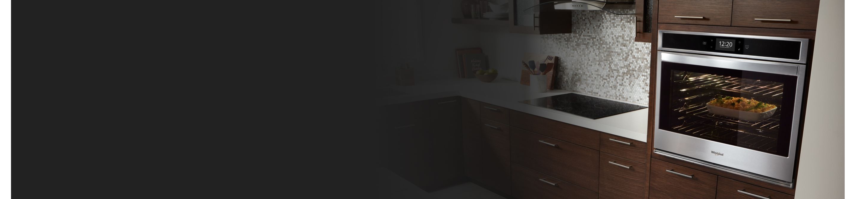 Whirlpool® oven set into wood paneling with casserole baking inside