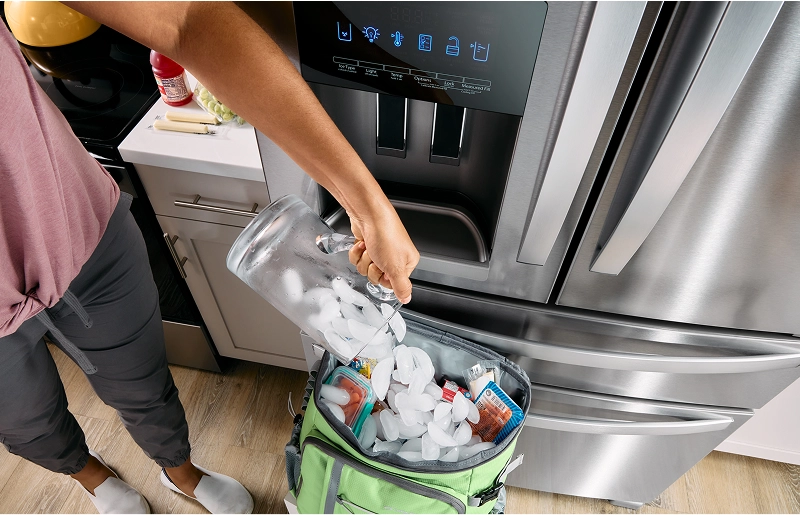 A person filling a cooler with ice cubes from their Whirlpool® Refrigerator's ice dispenser